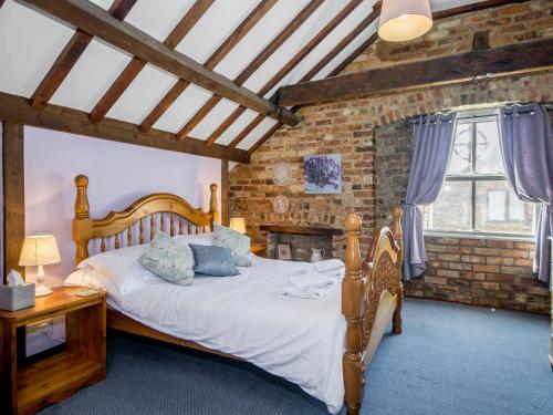 a bedroom with a wooden bed and a brick wall at Lavender Cottage II in Scalby