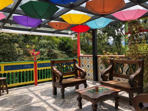 two chairs and a table under a colorful umbrella at 40 Amigos Hotel in Jardin