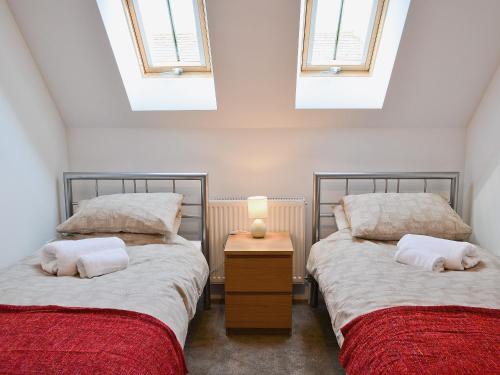 two beds in a room with two windows at Romany in Fletching