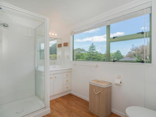 a bathroom with a shower and a sink and a mirror at Beach Beauty - Pauanui Holiday Home in Pauanui