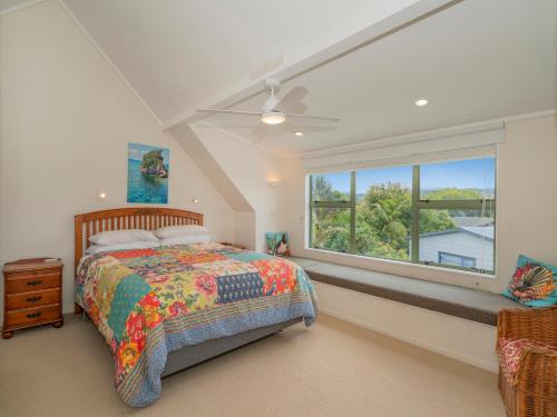 a bedroom with a bed and a large window at Beach Beauty - Pauanui Holiday Home in Pauanui