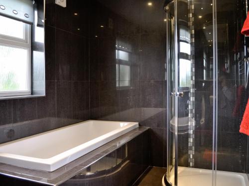 uma casa de banho com uma banheira e um chuveiro em vidro. em Y Bwythyn em Tavernspite