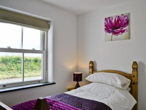 a bedroom with a bed and a window at Y Bwythyn in Tavernspite
