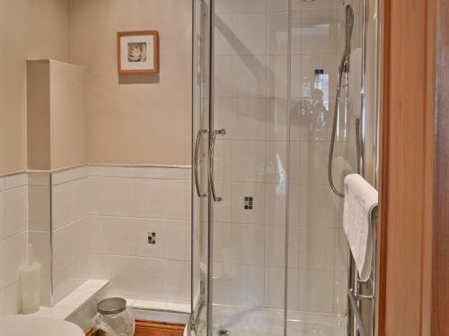 a shower with a glass door in a bathroom at Manor Farm Cottage in Carperby