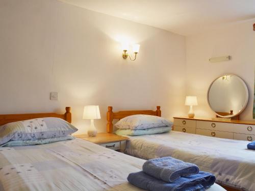 a bedroom with two beds and a mirror and lamps at Barn Owl Cottage in Cromford