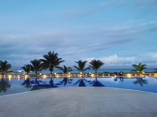 a large swimming pool with palm trees and the ocean at Pent House amazing View beachfront CANCUN in Cancún