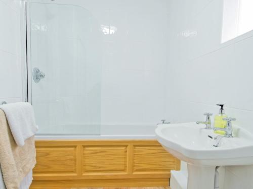 a white bathroom with a sink and a shower at Dairy Cottage - E5279 in Shincliffe