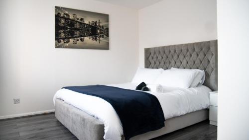 a bedroom with a large bed with a gray headboard at City service Apartment in Beeston