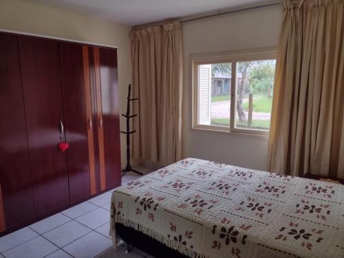 1 dormitorio con cama y ventana en casa a uma quadra do mar, en Torres