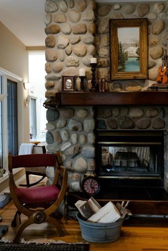 a living room with a stone wall with a fireplace at Lady MacDonald Country Inn in Canmore