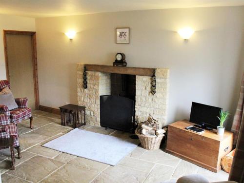 a living room with a fireplace and a tv at The Granary - E4753 in Ebrington