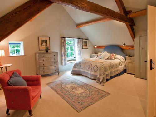 an attic bedroom with a bed and a chair at Warren Farmhouse in Kildale