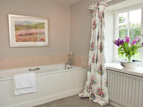 a bathroom with a bath tub and a window at Warren Farmhouse in Kildale