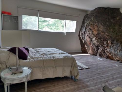 a bedroom with a bed and a large rock at Koba, una experiencia memorable in Potrero de los Funes