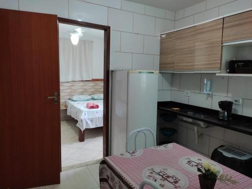 una pequeña cocina con mesa y nevera en Suite para temporada, en Arraial do Cabo