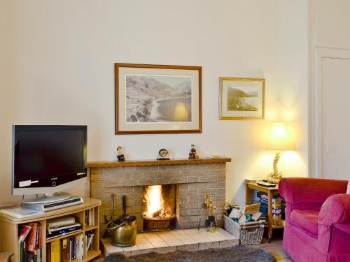 een woonkamer met een tv en een open haard bij Brightwater Cottage in Arnisdale