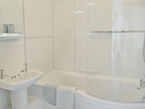 a white bathroom with a tub and a sink at Myrtle Loft in Instow