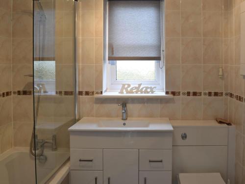 een badkamer met een wastafel, een douche en een raam bij Glendalough in Hunmanby