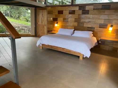 a bedroom with a bed with a wooden wall at Terrabambu Lodge in Mindo