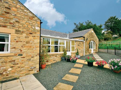 a stone house with a courtyard with potted plants at Granary Cottage - E4350 in Stanhope