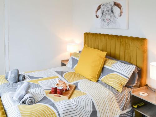 uma cama com cobertores e almofadas amarelos e azuis em Wellwood Cottage em Morpeth