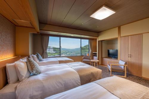 a hotel room with two beds and a large window at KAMENOI HOTEL Toba in Toba