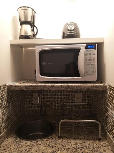 um micro-ondas sentado em cima de um balcão de cozinha em Flat 206 Hotel Cavalinho Branco (3 piscinas, elevador, sauna) em Águas de Lindóia