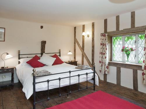 a bedroom with a bed with red pillows and a window at Old Hall Farm House in Saint James