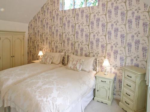ウィンタートン・オン・シーにあるCaptains Cottage - 27888のベッドルーム1室(紫色の花の壁にベッド1台付)