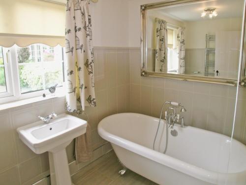 a bathroom with a tub and a sink and a mirror at Captains Cottage - 27888 in Winterton-on-Sea