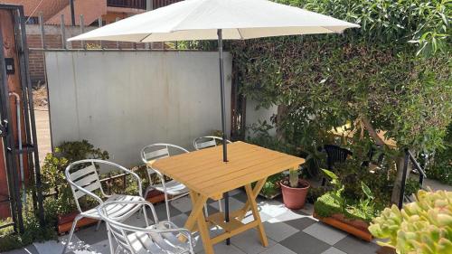 a wooden table and chairs with an umbrella at Hostal New Do Rio in Maitencillo