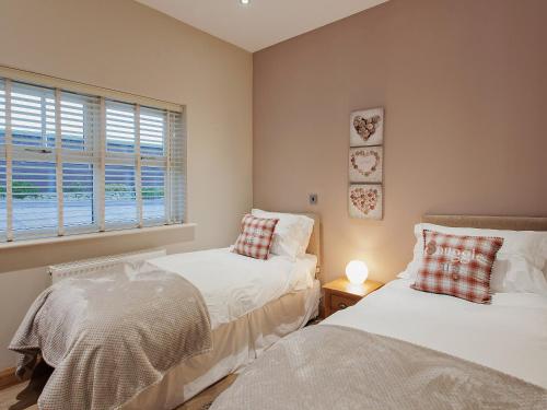 a bedroom with two beds and a window at Two The Old Stables in Knitsley