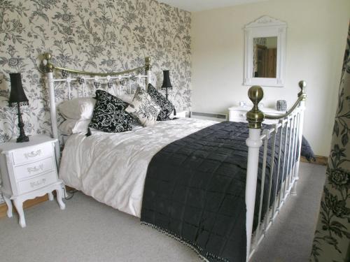 a bedroom with a white bed with a black blanket at Rundales Cottage in Appleby