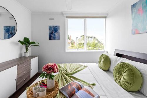 um quarto branco com uma cama com almofadas verdes em Bright and Sunny Gem on Hotham em Melbourne