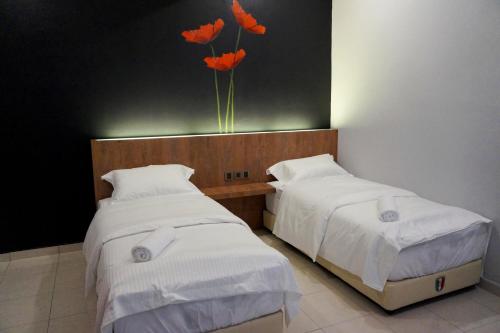 two beds in a room with orange flowers on the wall at Urbanstay Kuantan in Kuantan