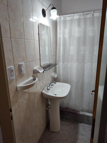 y baño con lavabo, espejo y cortina de ducha. en Alojamiento Turistico Mainque, en Las Grutas