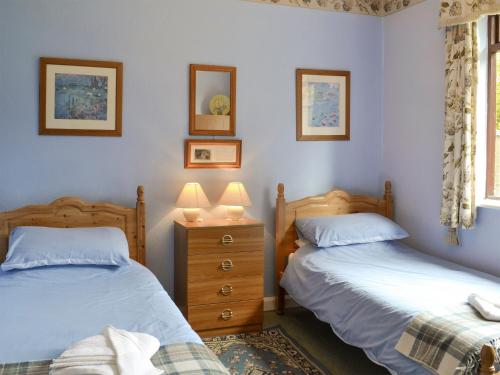 a bedroom with two beds and a dresser with two lamps at Peasholm in Thornton Dale