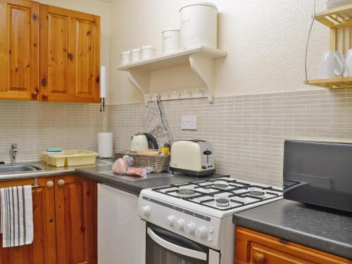 a kitchen with a white stove and a sink at Stable Cottage - 29155 in Staintondale