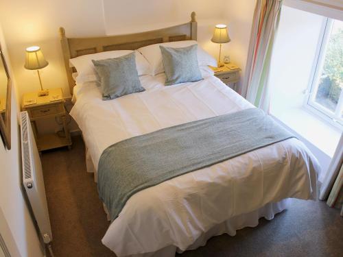 a bedroom with a large bed with two lamps and a window at Nutmeg Cottage in Tideswell