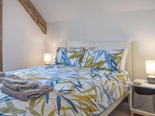 łóżko z niebieską i żółtą kołdrą i dwoma lampami w obiekcie Dairy Barn - Uk37424 w mieście Langtree