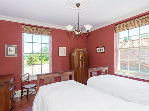 a red bedroom with two beds and two windows at Tilney Hall in Terrington Saint John