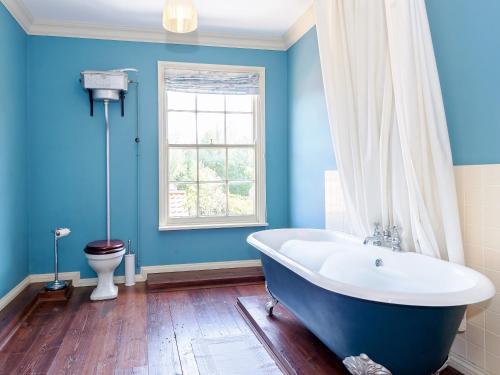 uma casa de banho azul com uma banheira e um WC em Tilney Hall em Terrington Saint John