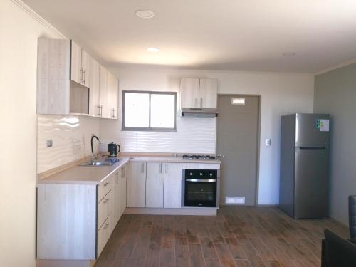 a kitchen with white cabinets and a black refrigerator at Curacautín Lodge in Curacautín