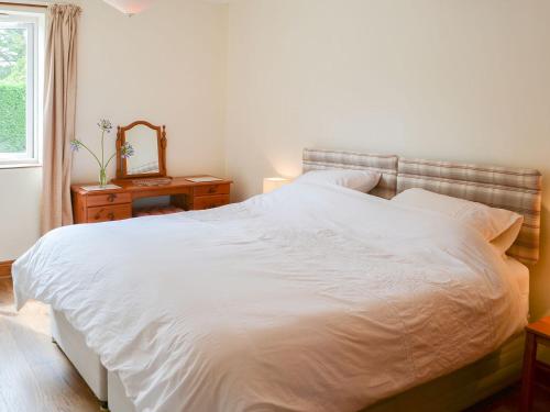 a bedroom with a white bed and a mirror at The Conifers in Hevingham