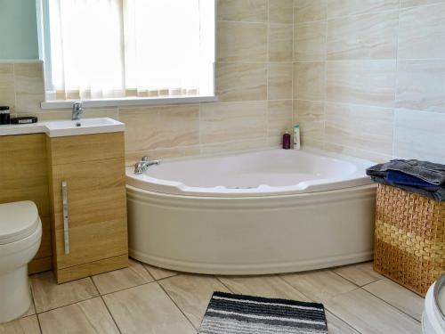 a bathroom with a tub and a toilet and a sink at Sewerby Cottage in Sewerby