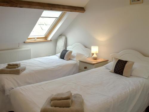 two twin beds in a room with a window at Bay - E4482 in Ludham