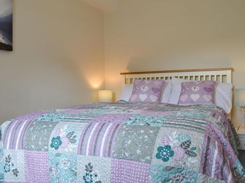 a bedroom with a bed with a pink and purple comforter at The Retreat in Nether Wasdale