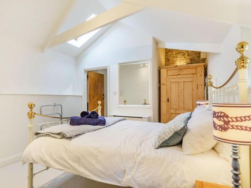 een witte slaapkamer met een bed en een raam bij Curlews in Newlyn