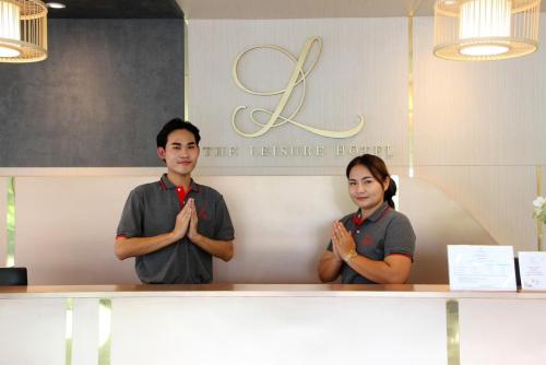 a man and woman standing behind a table with their hands folded at The Leisure Hotel in Bang Bo