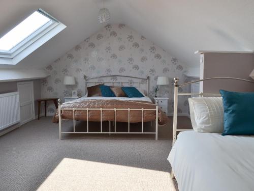 a bedroom with a bed with blue pillows and a window at Encil-y-mor in Criccieth